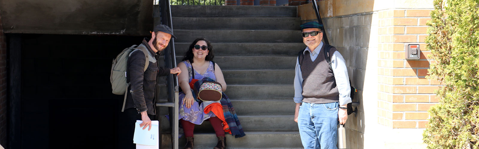 Three members of the faculty chat on the steps of Camden Hall